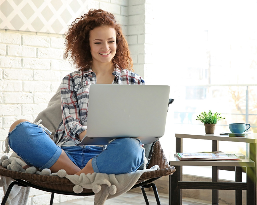 women sitting on a comfy chair with a laptop having online therapy in Pacifica