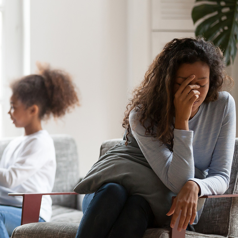 Woman sitting on a chair in front of her child, in need of parenting support