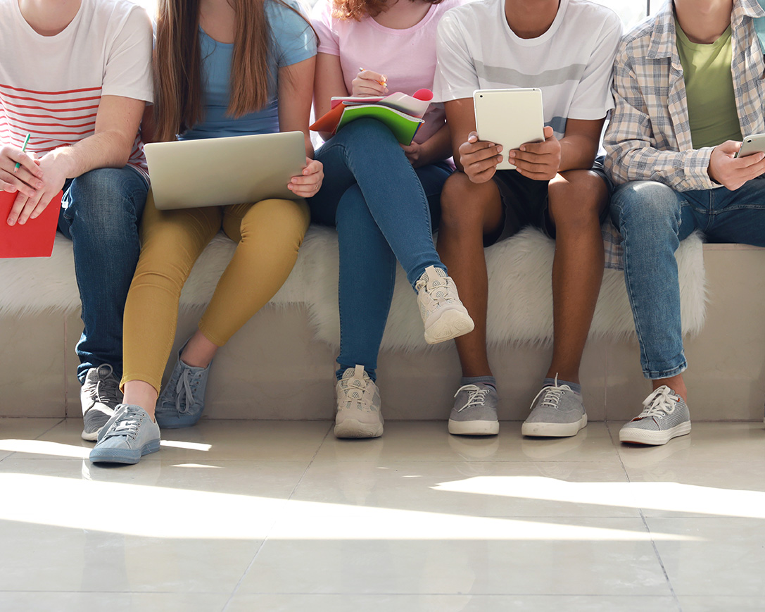 Group of teenagers on mobile devices outside of school in Pacifca, CA