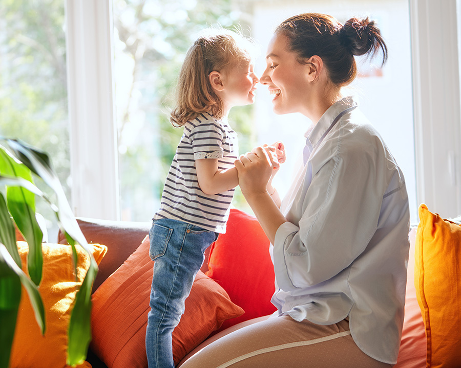 Mom and young daughter on a couch in living room