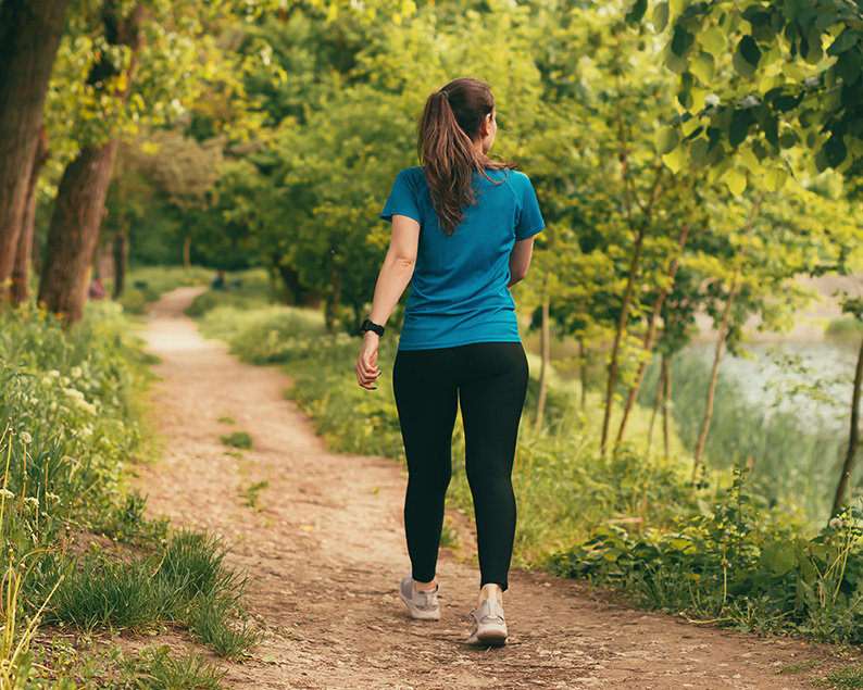 Woman walking on a path. Walking therapy benefits the mind and body.